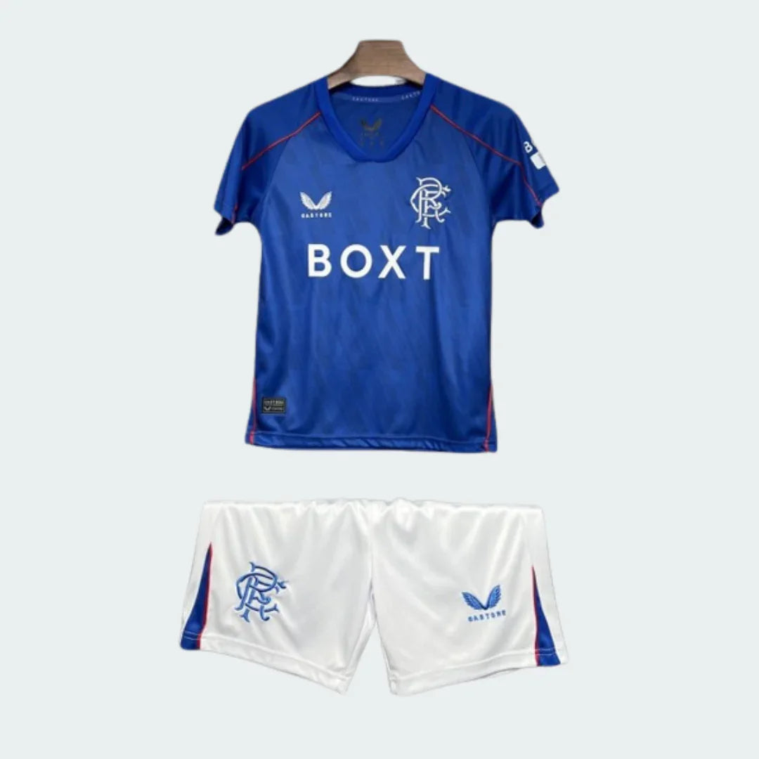 Kit infantil do Rangers, camisa azul com detalhes em vermelho, patrocínio BOXT e escudo do clube, e shorts brancos com escudo.