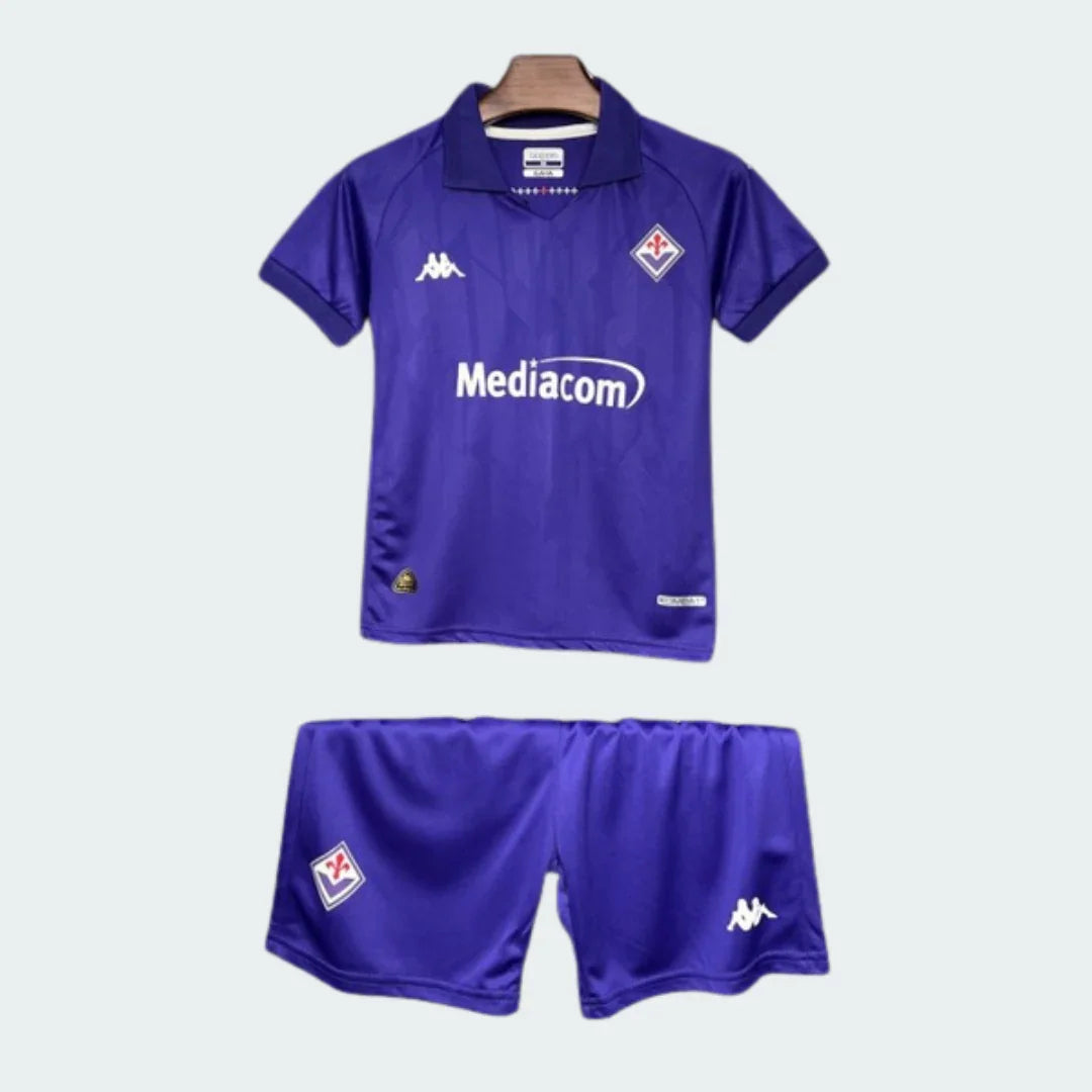 Kit infantil roxo da Fiorentina com camisa e shorts. Camisa com gola polo, escudos Kappa e Fiorentina, e patrocinador Mediacom.
