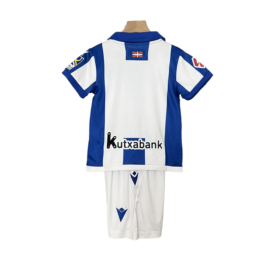 Kit oficial infantil Mini Mantos Real Sociedad Macron. Camisa e shorts azuis e brancos