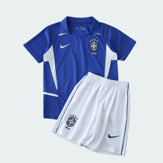 Kit infantil da seleção do Brasil II 2002, com camisa azul polo e shorts brancos. Possui escudo do Brasil e logo da Nike.