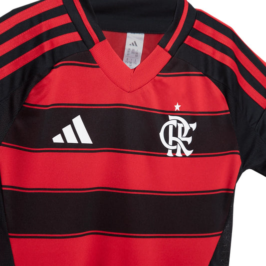 Close-up da camisa infantil do Flamengo, listrada em vermelho e preto, com escudo do time e logo Adidas em branco no peito.