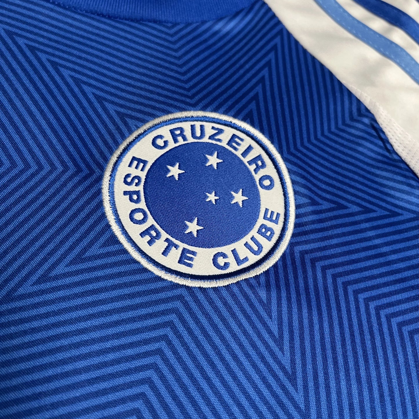 Detalhe da camisa oficial infantil do Cruzeiro, kit Mini Mantos. Distintivo bordado azul com estrelas brancas