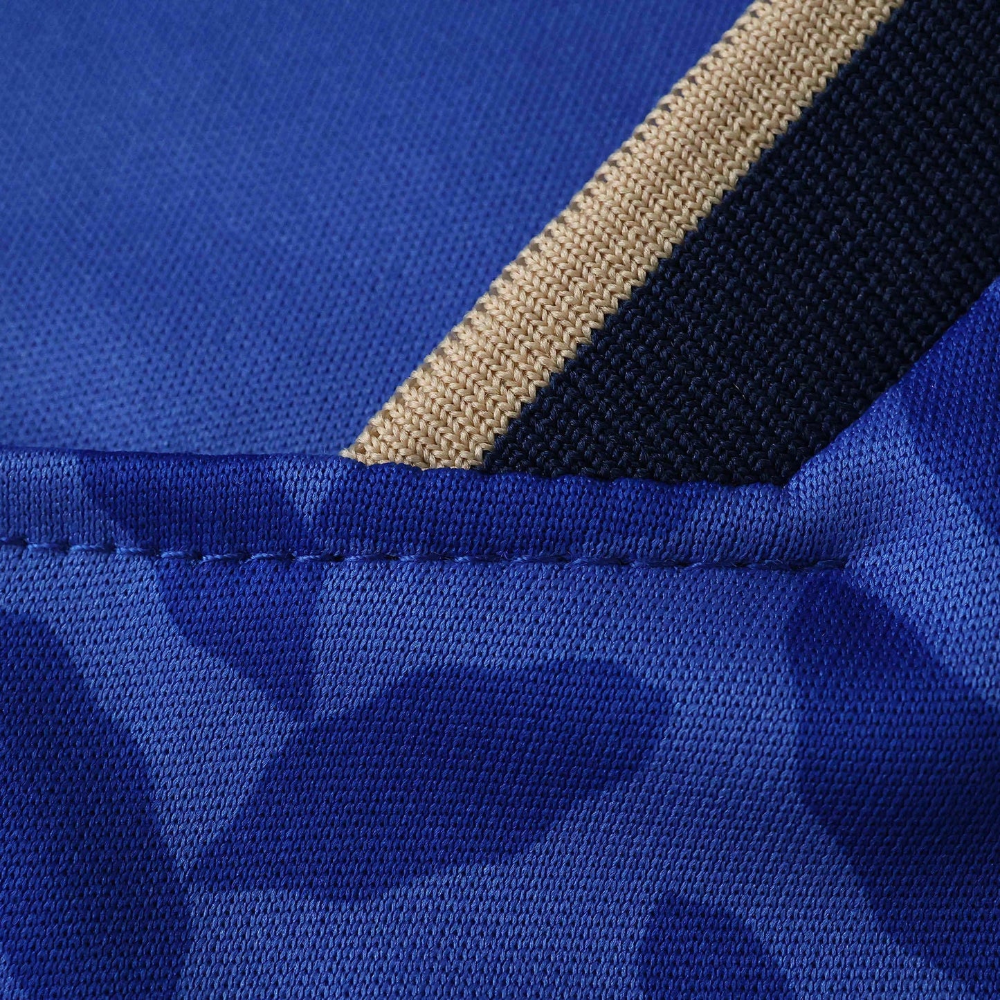 Detalhe de costura e tecido de malha azul royal com listras bege e azul marinho.