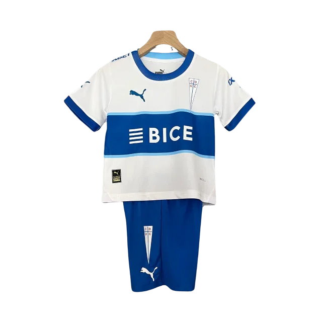 Kit infantil Universidad Católica 24/25. Camisa branca com listras azuis horizontais, logo BICE e escudo do clube. Short azul com escudo.