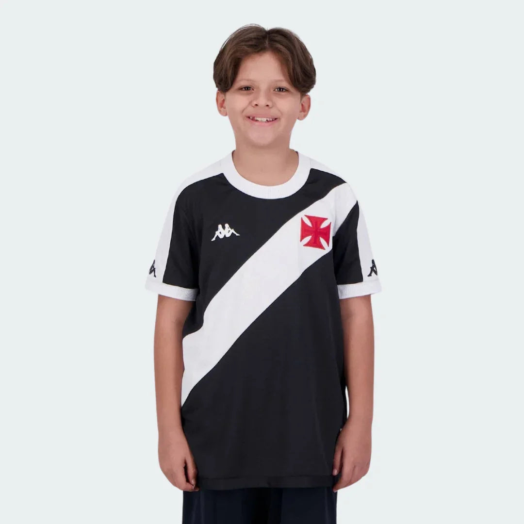 Foto de menino sorrindo, vestindo camisa de futebol infantil preta do Vasco com faixa diagonal branca, escudo e logo Kappa.