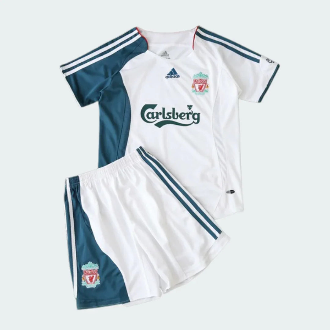 Kit infantil Liverpool retrô 2006, camisa e shorts brancos com detalhes em verde petróleo, listras brancas e escudo.