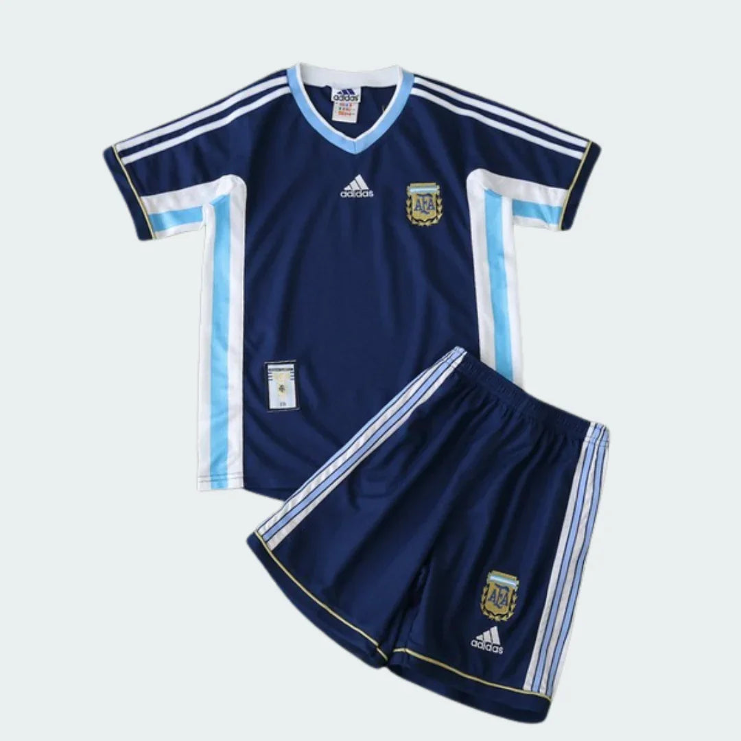 Kit infantil retrô Argentina 1998, azul marinho com detalhes em branco e azul claro. Camisa e shorts com escudo da Argentina e logo Adidas.