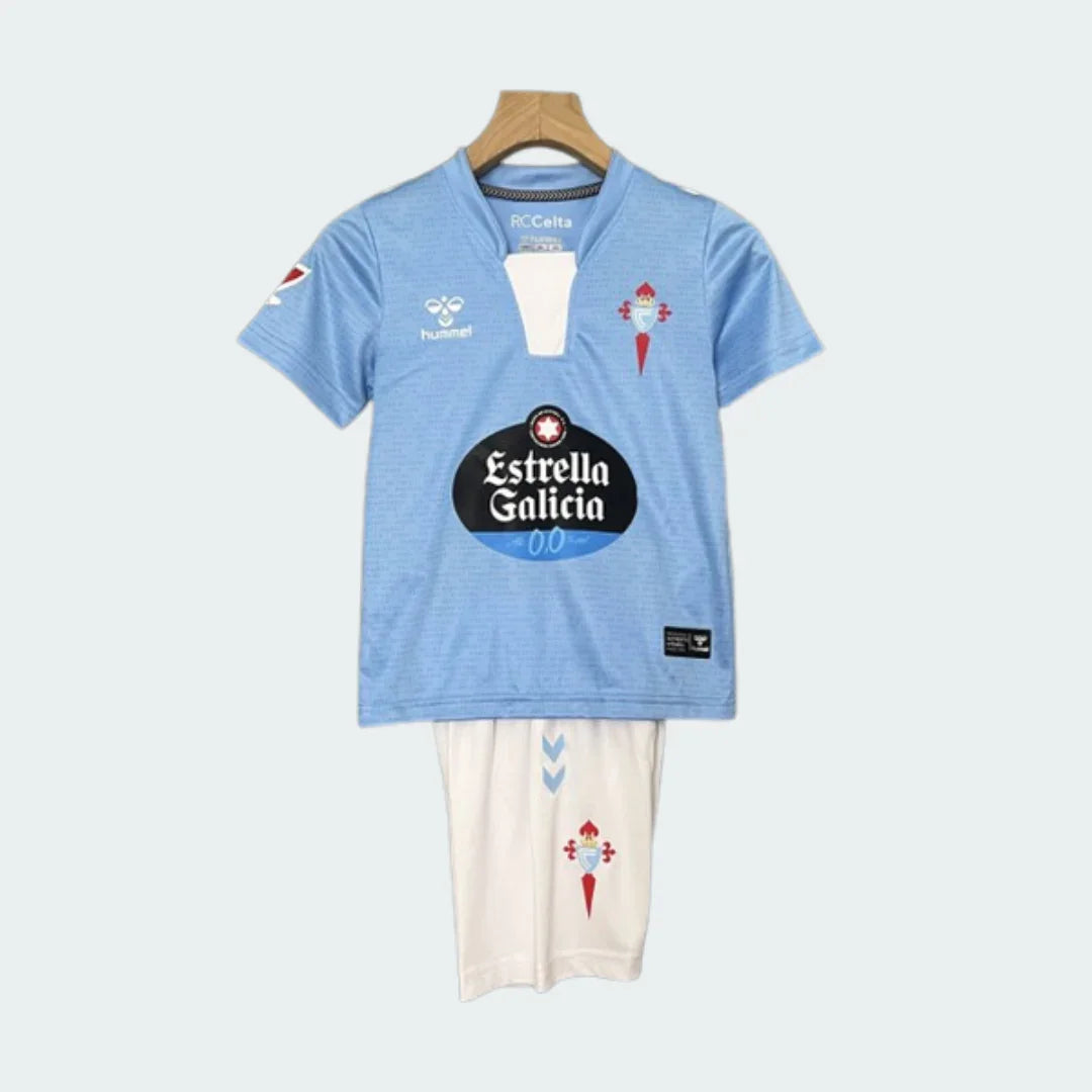 Kit Infantil Celta Vigo I 24/25. Camisa azul claro e shorts creme com escudos do Celta Vigo e logos Hummel e Estrella Galicia.