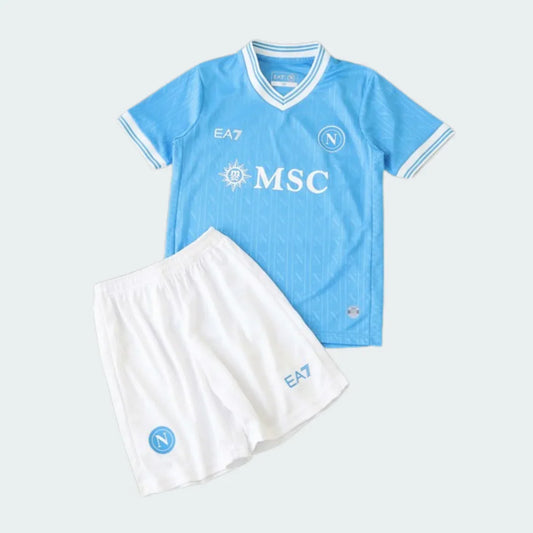 Kit de futebol infantil do Napoli I 25/26, incluindo camisa azul-claro com logos brancos e shorts brancos com logos azul-claro.