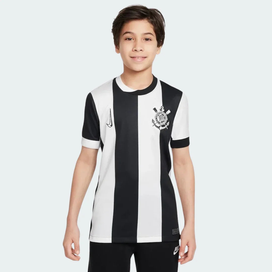 Foto de um menino sorrindo, vestindo a camisa listrada preta e branca do Timão, com o escudo e o símbolo da Nike.