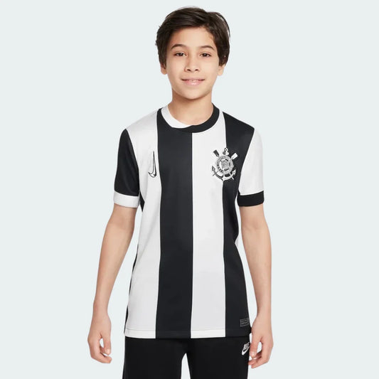Foto de um menino sorrindo, vestindo a camisa listrada preta e branca do Timão, com o escudo e o símbolo da Nike.
