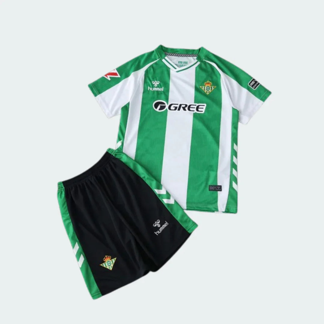 Kit infantil Real Betis 25/26 com camisa listrada verde e branca, shorts pretos, e logos Hummel, GREE e escudo do clube.
