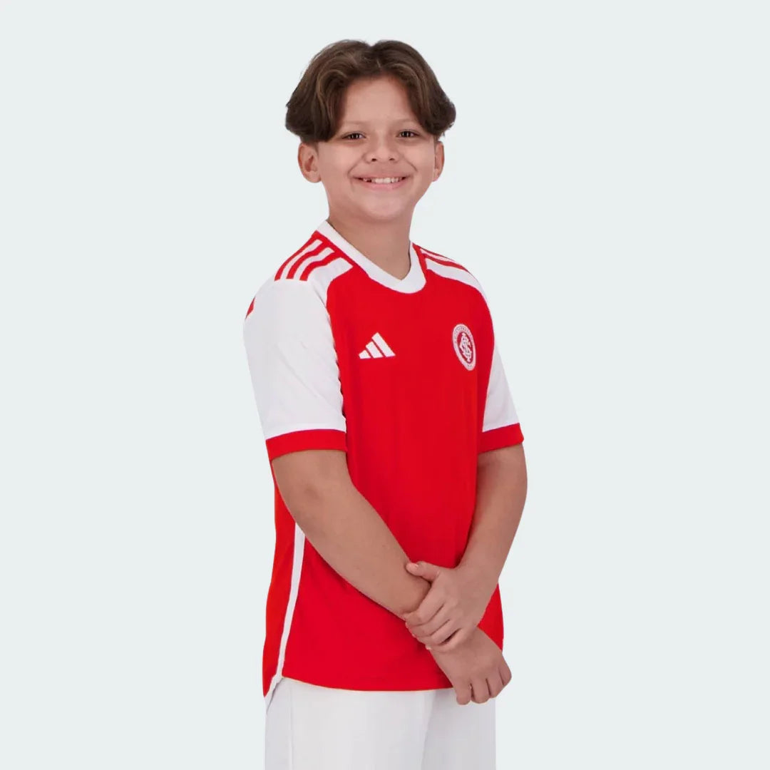 Kit camisa oficial Internacional infantil Mini Mantos. Menino sorrindo, vestindo uniforme vermelho e branco