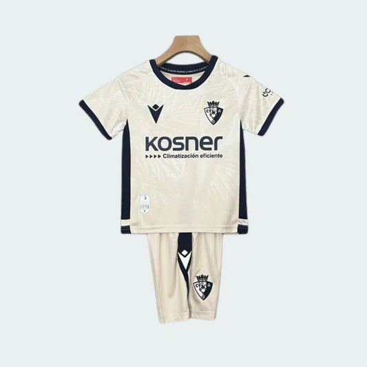 Kit infantil Osasuna II 24/25, com camisa e shorts off-white e detalhes azul-marinho, pendurado em cabide.
