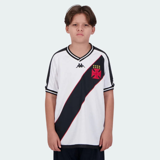 Menino veste camisa branca do Vasco com faixa diagonal preta, escudo vermelho, estrelas douradas e logo Kappa preto.