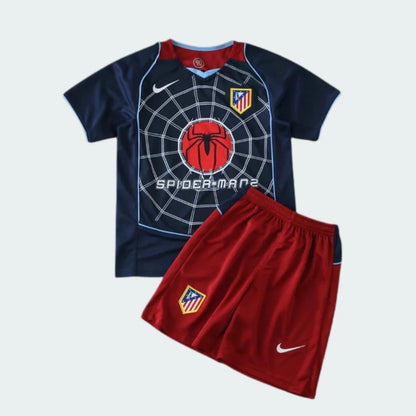 Kit infantil de futebol Atlético de Madrid, com camisa azul escura e shorts vermelhos. Camisa tem estampa de teia de aranha e logo do Homem-Aranha no peito.