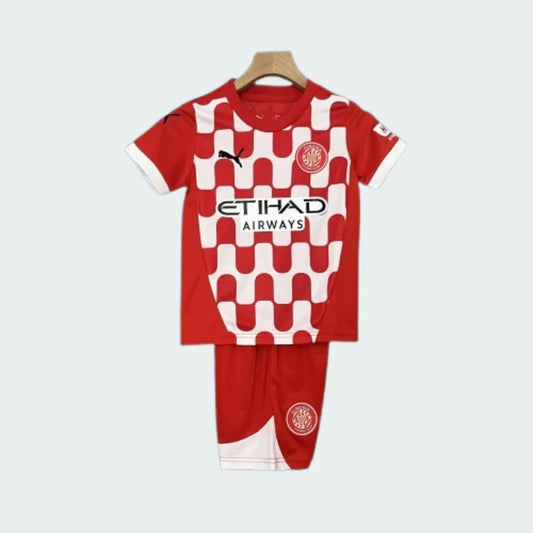 Kit infantil do Girona com camisa vermelha e estampa quadriculada branca e vermelha no peito, e calção vermelho.