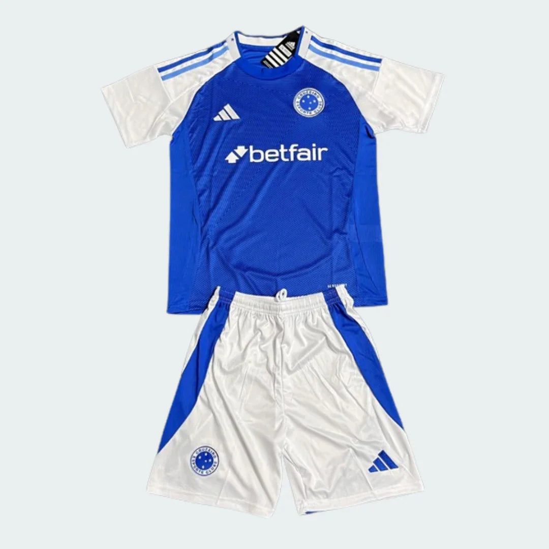 Kit infantil Cabuloso 25/26, camisa azul e shorts brancos. Destaques: mangas brancas, listras nos ombros, logos Adidas e Betfair.