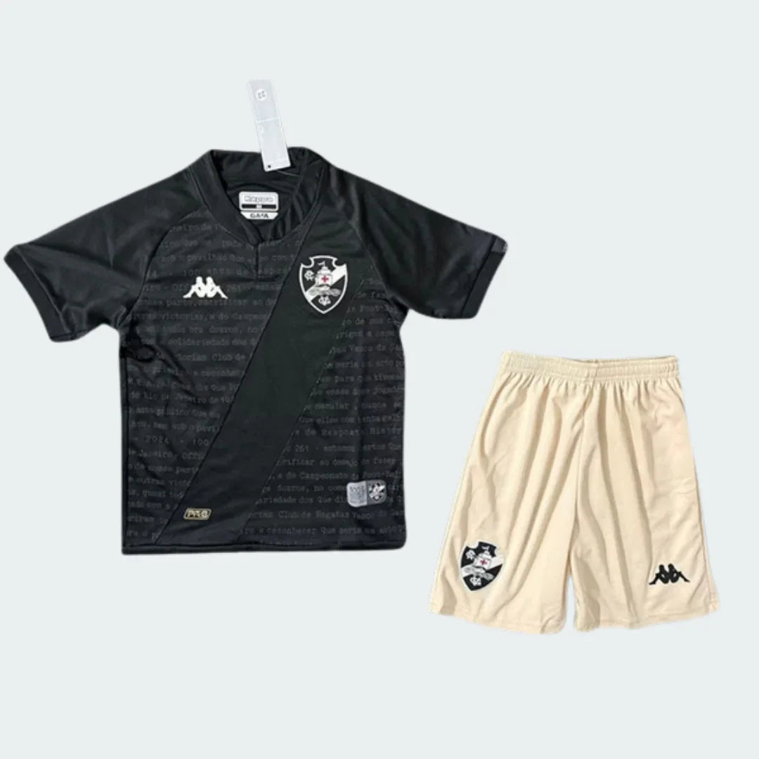 Kit infantil Vasco da Gama preto com faixa branca diagonal e shorts creme/bege. Escudos do Vasco e logos Kappa visíveis.