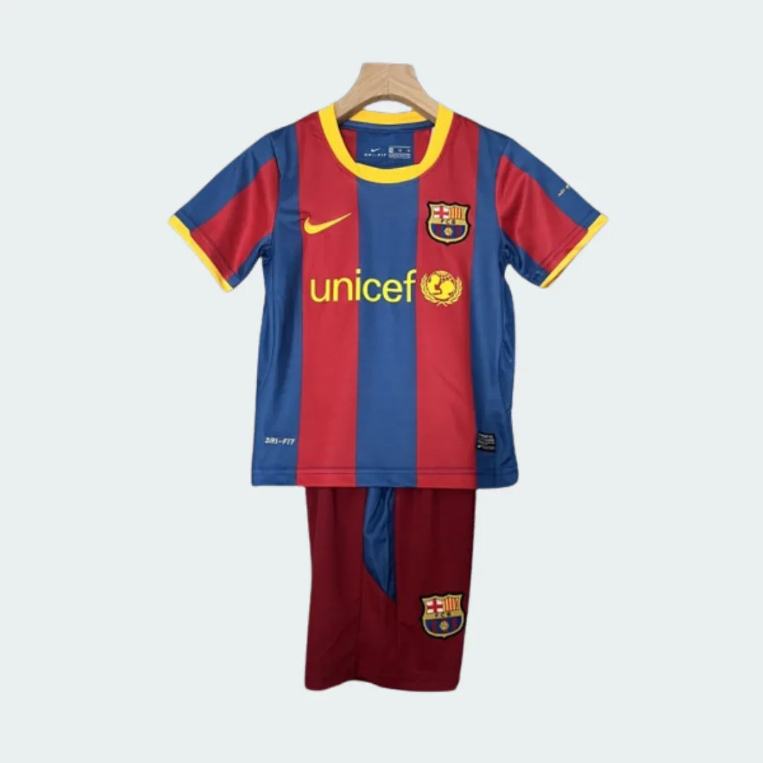 Kit infantil retrô do Barcelona 10/11 com camisa de listras vermelhas e azuis, gola e punhos amarelos, shorts vinho e escudo do time.