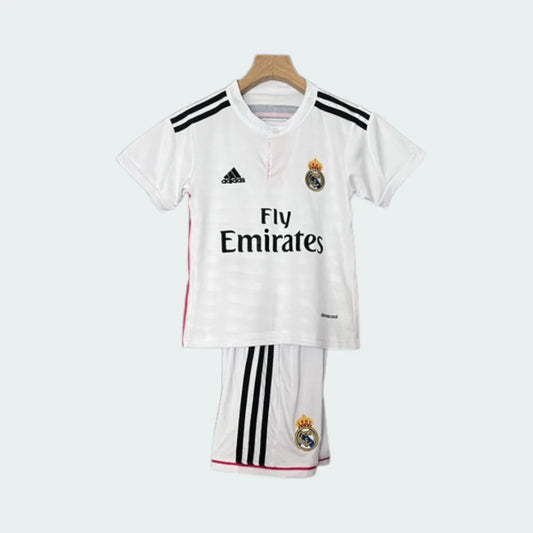 Foto de kit infantil do Real Madrid 14/15, camisa branca com listras pretas e shorts brancos, pendurado em cabide.