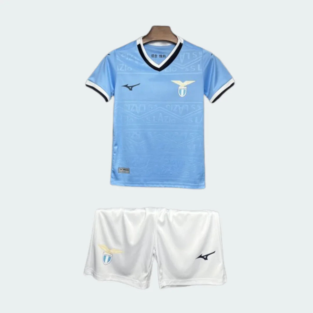 Kit infantil Lazio completo com camisa azul celeste e shorts brancos. A camisa tem gola V, escudo do time e logo Mizuno. Os shorts também têm escudo e logo Mizuno.