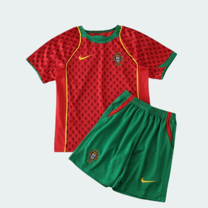 Kit infantil de futebol Portugal 2004 em vermelho e verde, com camisa vermelha estampada, shorts verdes, escudos de Portugal e logos Nike.