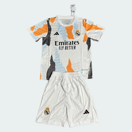 Kit infantil Real Madrid treino 25/26. Camisa branca com detalhes abstratos laranja, azul e preto, escudo do clube e patrocinador. Shorts brancos com escudo e logo Adidas.