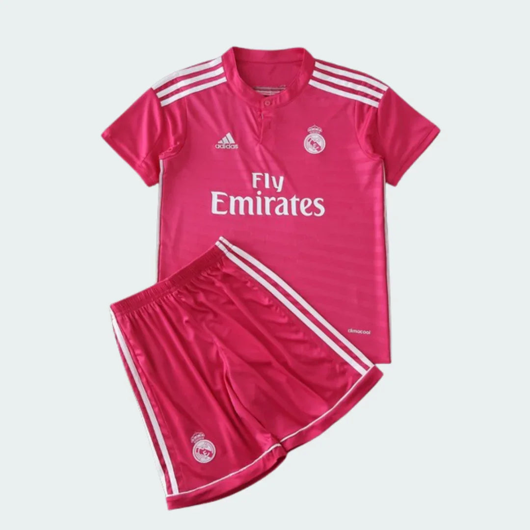 Kit infantil do Real Madrid 14/15 rosa. Camisa de futebol e shorts rosa com detalhes brancos e escudos do clube.