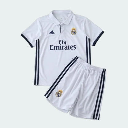 Kit infantil Real Madrid 16/17 branco: camisa polo com escudo, Adidas, Fly Emirates e shorts com escudo, listras escuras laterais.
