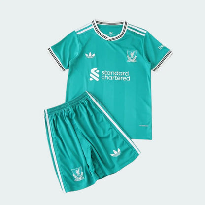 Kit infantil de futebol verde-água (camisa e shorts). Inclui listras brancas, logos Adidas, Standard Chartered e escudo com pássaro mítico.