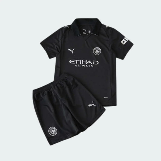 Kit infantil completo do Manchester City 25/26, camisa e shorts pretos. Logos Puma, escudo e Etihad Airways em branco.