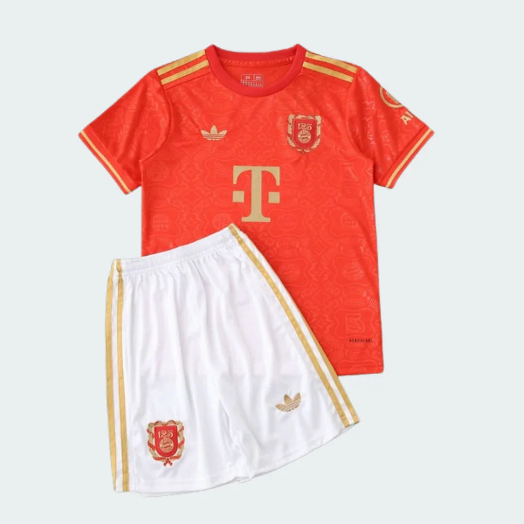 Foto de estúdio do kit infantil Bayern de Munique I 24/25. Camisa vermelha com detalhes dourados e shorts brancos com listras douradas.
