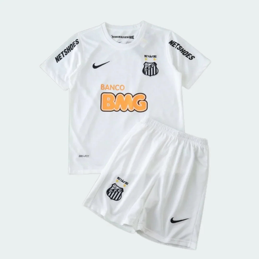 Kit de futebol infantil branco com camisa e shorts. Camisa tem escudo preto e branco, logo Nike, patrocinadores NETSHOES e BANCO BMG laranja.