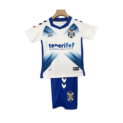 Kit infantil Tenerife I 24/25, camisa e shorts azul-marinho com detalhes amarelos, logo Hummel e escudo do Tenerife, em fundo preto.