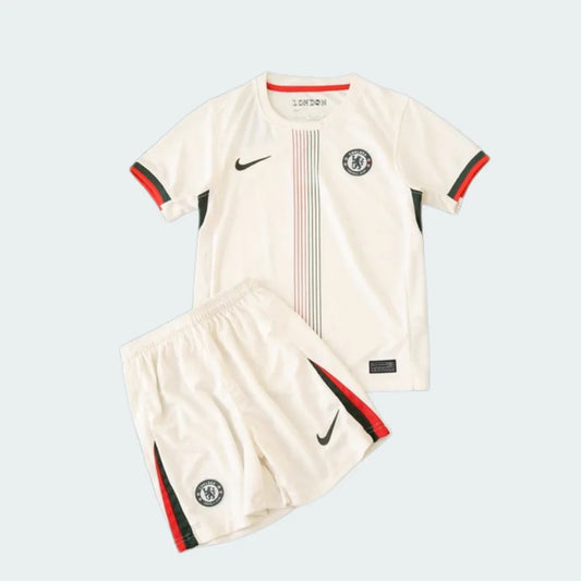Kit infantil Chelsea II 25/26 com camisa e shorts creme. Detalhes em preto e vermelho, listras verticais na camisa, logos Nike e escudo.