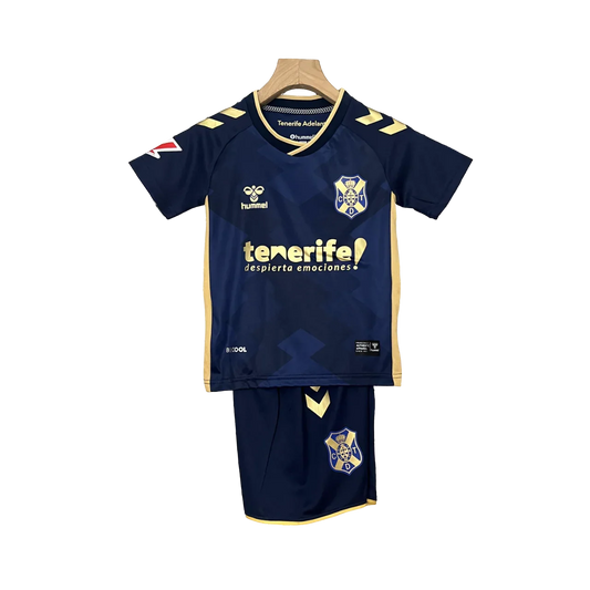 Kit infantil Tenerife II 24/25, camisa e shorts azul-marinho com detalhes amarelos, logo Hummel e escudo do Tenerife, em fundo preto.