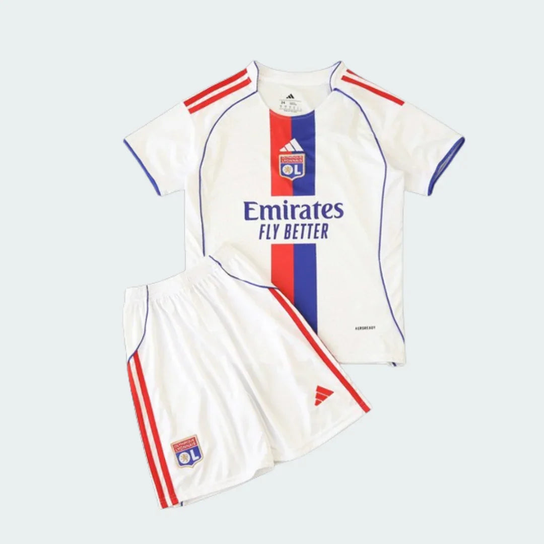 Kit infantil branco do Lyon com camisa e shorts. A camisa possui faixa vertical azul e vermelha, escudo do clube e patrocinador. Shorts com listras vermelhas.