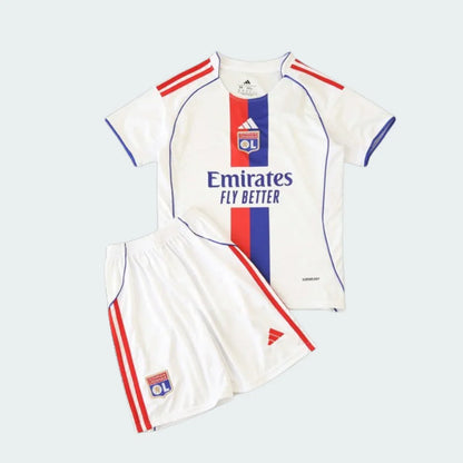 Kit infantil branco do Lyon com camisa e shorts. A camisa possui faixa vertical azul e vermelha, escudo do clube e patrocinador. Shorts com listras vermelhas.