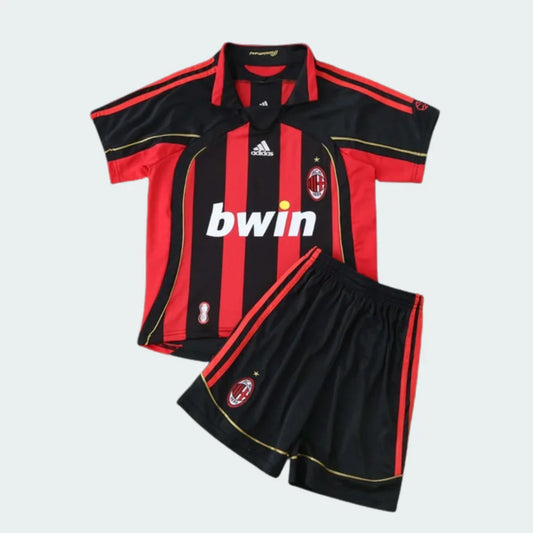 Foto de um kit infantil retrô Milan, camisa listrada vermelha e preta, shorts pretos, com escudos e patrocínio bwin.