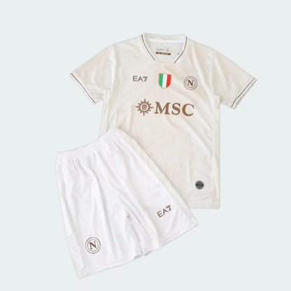 Kit infantil Napoli II 25/26 branco com detalhes marrons, camisa e shorts. Logos EA7, escudo Napoli, MSC e emblema italiano.