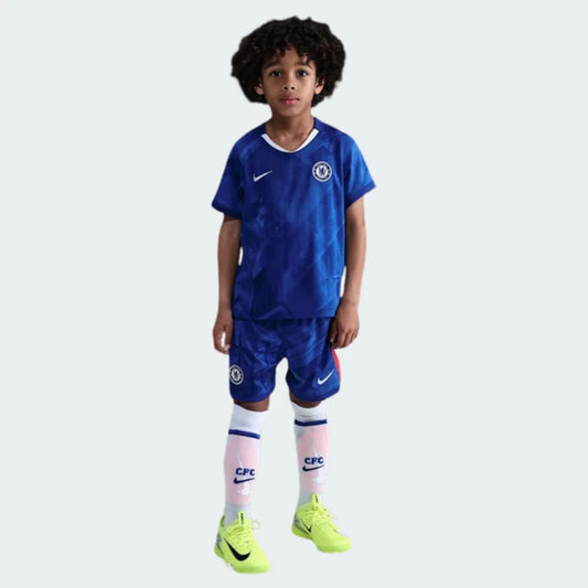 Menino vestindo kit infantil do Chelsea, com camisa e calção azul royal texturizado e meiões brancos.