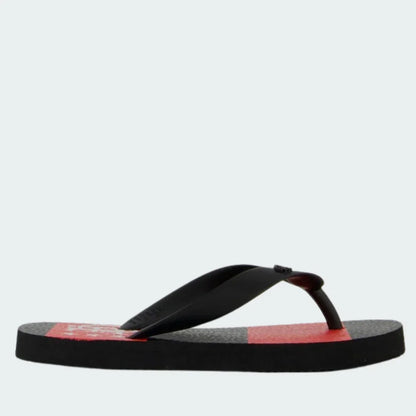 Chinelo preto e vermelho com solado estampado e tiras pretas, em fundo branco liso.