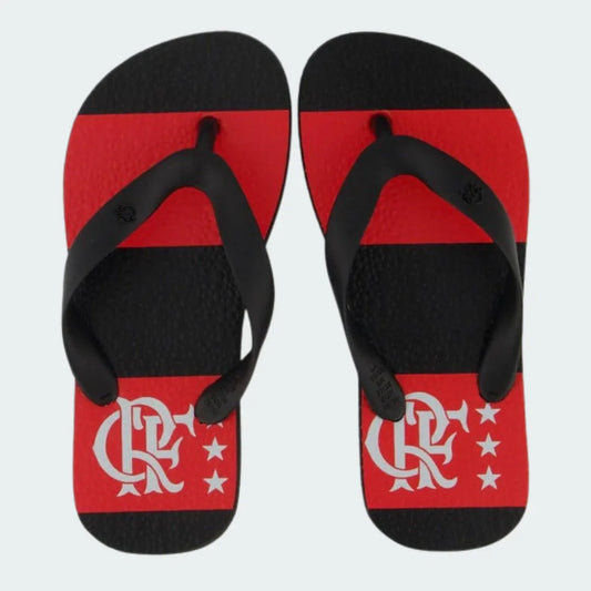 Um par de chinelos infantis do Mengão com solado listrado em preto e vermelho, correias pretas e o escudo CRF branco com três estrelas.