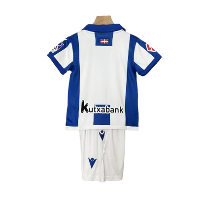 Kit oficial infantil Mini Mantos Real Sociedad Macron. Camisa e shorts azuis e brancos