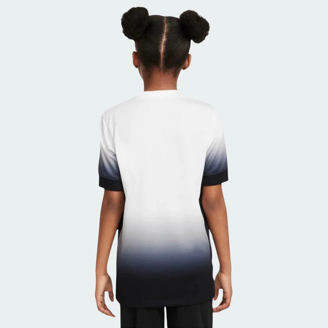 Foto de costas de criança usando camiseta infantil degradê branca e preta, com mangas curtas escuras e gola clara.