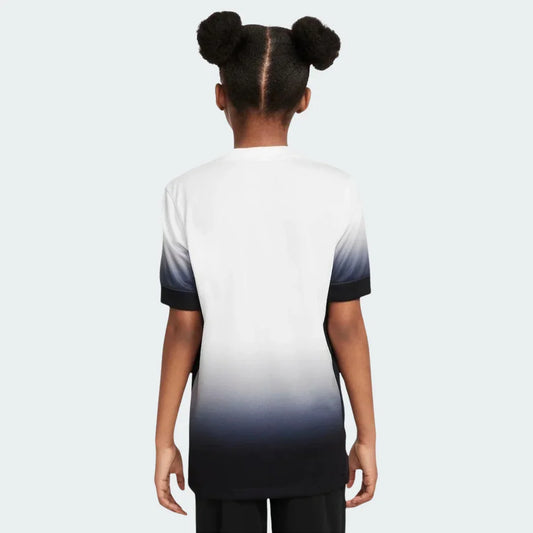 Foto de costas de criança usando camiseta infantil degradê branca e preta, com mangas curtas escuras e gola clara.