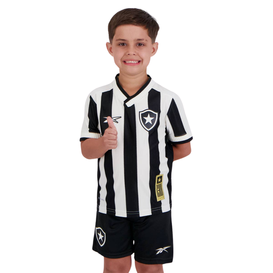 Menino vestindo kit infantil do Botafogo, com camisa listrada em preto e branco e calção preto com escudo.