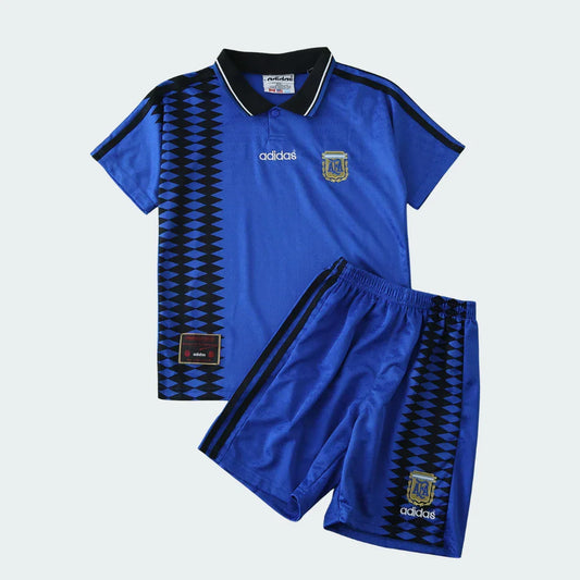 Kit infantil retrô da Argentina de 1994, com camisa e shorts azuis, detalhes em preto e branco, escudo da Argentina e logo Adidas.