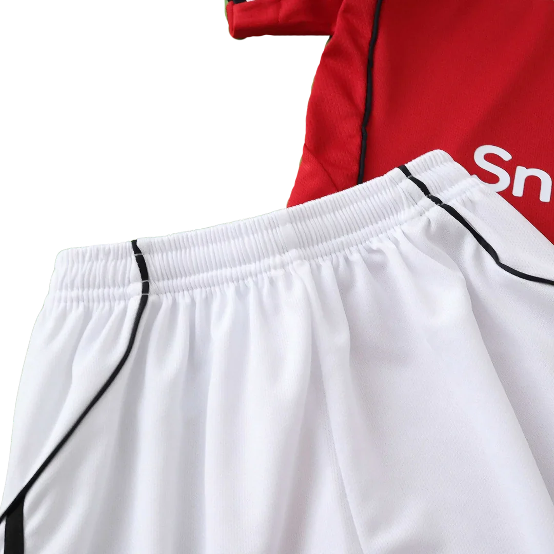 Kit de futebol infantil com camisa vermelha e detalhes brancos, e shorts brancos com detalhes pretos na lateral. Cós elástico.